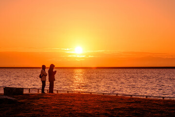 Fototapeta na wymiar 海から昇る日出と二人。神戸六甲アイランドのマリンパークで撮影