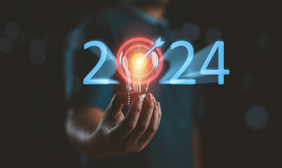 Businessman holding light bulb with target 2023 to 2024 for preparation happy new year concept. New...