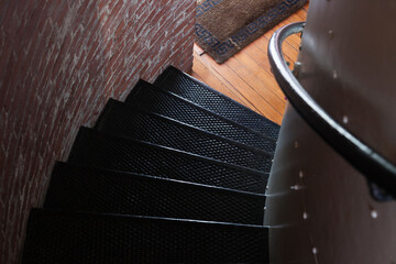 Spiral stairs, a staircase with a railing twisting and turning in a small space, a brick wall.