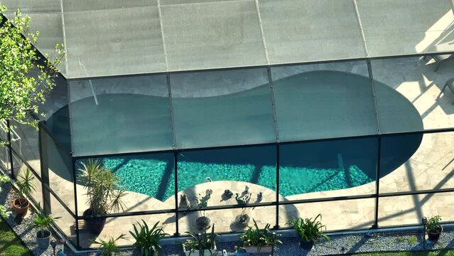 Top view of contemporary american private home with outside lanai enclosure over large swimming pool. Concept of outdoor living and having good time in pool water on warm Florida summer sun