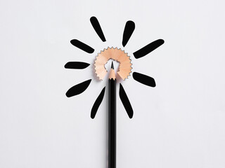 Education concept. Black pencil tip surrounded by its shaving representing a flower shape on white...