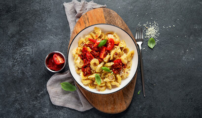 Traditional italian food. Dish with ravioli, tomato, Sun-dried tomatoes, basics and grated cheese. Tasty pasta