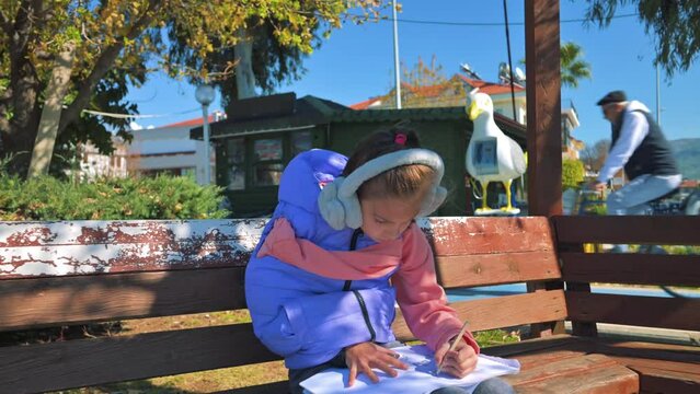 Girl sitting on the bench and drawing with the pencil. 4k video footage UHD 3840x2160 in slow motion