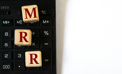 MRR - acronym on wooden cubes against the background of a calculator. Copy space