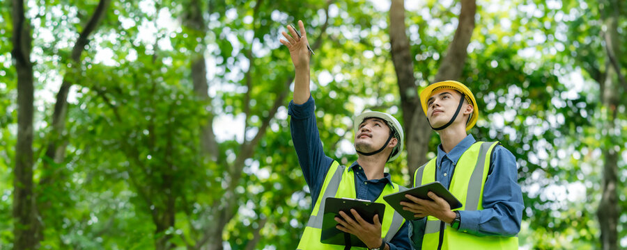 Two male engineers wear safety helmets on their heads. Check the weather conditions of nature and environment. Ready to use technology to work with digital tablets at renewable energy farms on tablets