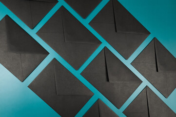 Top view of black envelopes on green background. Post flat lay, copy space.