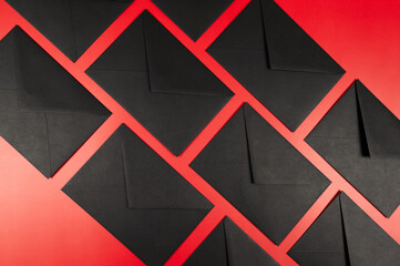 Top view of black envelopes on red background. Post flat lay, copy space.