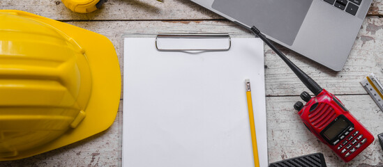 work environment with a laptop, a yellow hard hat, calculator, level, screwdriver, and folding...