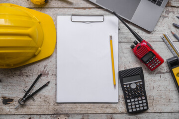 work environment with a laptop, a yellow hard hat, calculator, level, screwdriver, and folding...
