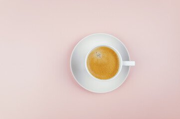 Top view of coffee cup on light pink background. White cup with plate, flat lay, copy space.