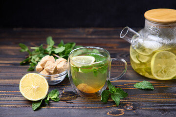 natural organic herbal tea with lemon and mint in glass teapot on a wooden table