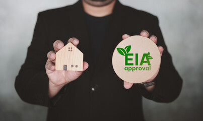 Businessman holding the approval EIA and home model. Environmental Impact assessment is the...