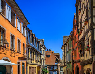 Fototapeta premium Ornate traditional half timbered houses with blooming flowers in a popular village on the Alsatian Wine Route in Riquewihr, France