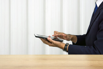 A focused businessman in dark blue suit typing on tablet computer. Side view. Digital Life Exploration.