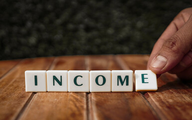 Income written with letters being kept in front of green blur background 