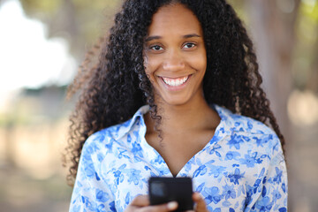 Happy woman looking at you holding smart phone
