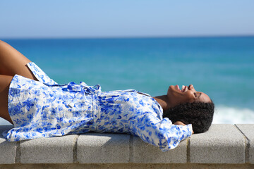 Happy black woman lying on the beach resting