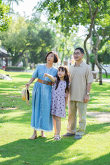 Naklejka na ściany i meble Happy Asian family enjoying leisure time with outdoor activities in a public park.