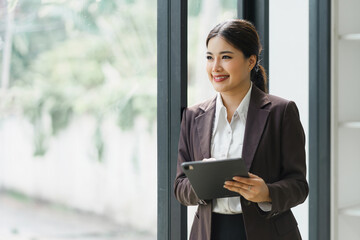 Professional Businesswoman standing and using Digital Tablet at modern office.