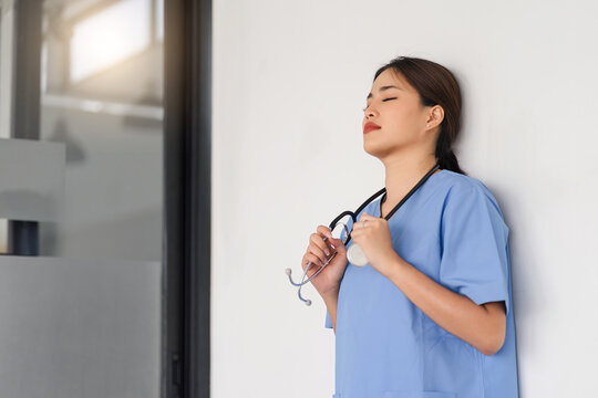 Tired, exhausted nurse or doctor taking a break in the clinic corridor and resting after a hard day.