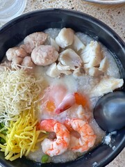boiled rice clear soup with shrimp in a ceramic bowl on wooden table. homemade style food concept.