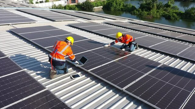 Engineering technician is professional trained in skills and techniques installing solar photovoltaic panels system on power industrial factory roof, Engineering concepts to good environment.