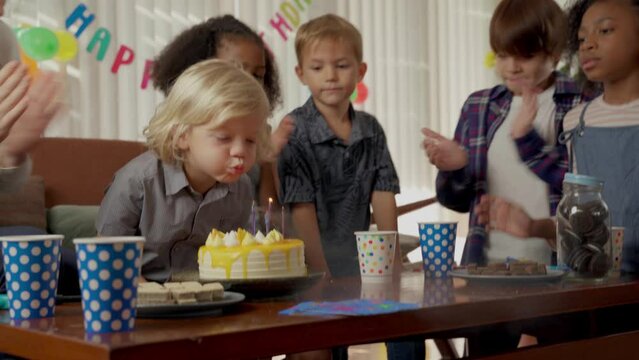 Little boy blowing out candles on his birthday cake