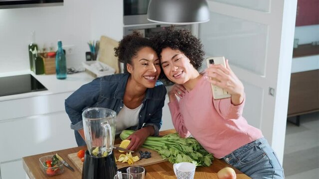 Friends taking selfie in kitchen while preparing healthy smoothies