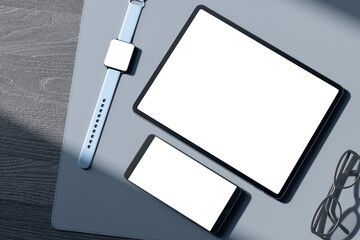Top view of empty white tablet and cellphone screen, digital watch, pen and glasses on gray wooden...