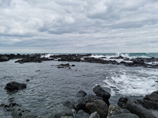 Fototapeta na wymiar This is a Jeju Island beach with basalt rocks.