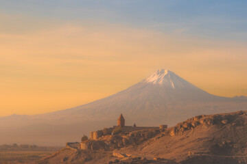 Closeup of Ararat mountains with the old Khor Virap monastery at fall sunrise and orange sky....