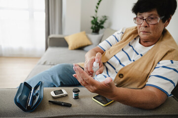 Senior woman using sanitizer for blood sugar testing at home