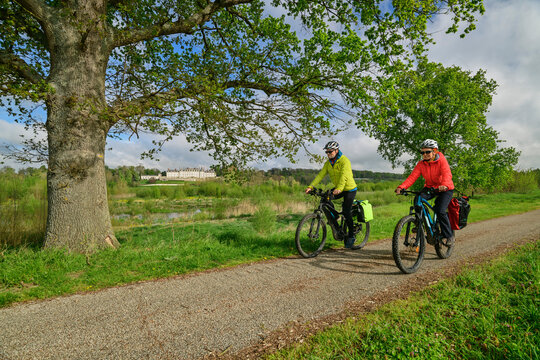 France, Centre-Val de Loire, Man and woman cycling along dirt road inLoire Valley