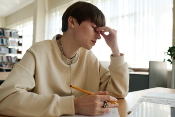 Tired student rubbing eyes in library