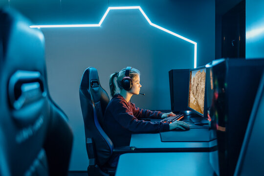 Gamer sitting on chair and playing video game on desktop PC
