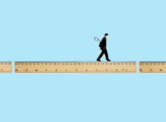 Man walking on broken ruler with wind-up key against blue background