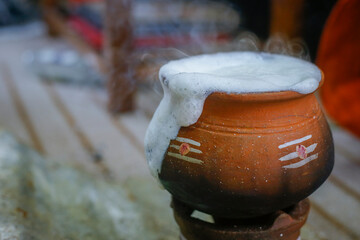 Old pot used for boiling milk in focus.