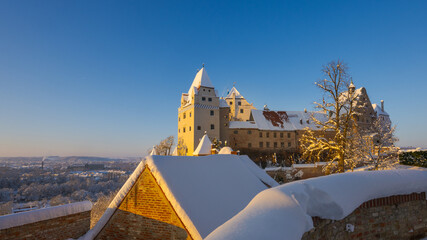 The outside of Castle Trausnitz in Landshut, Lower Bavaria with snow covered walls and roofs in winter on sunny day