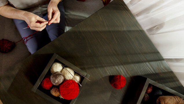 Senior woman knitting with needles on table at home