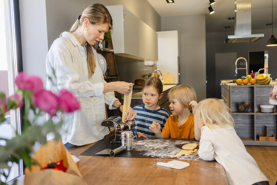 Family cutting dough with pasta maker at home