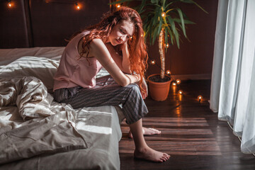 Sad young woman lying in bed