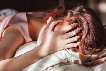 Sad young woman lying in bed