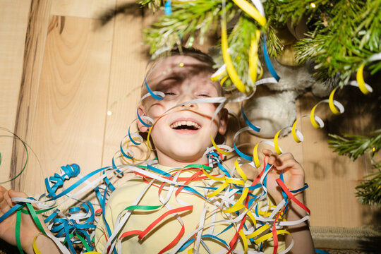 Cheerful boy lying with party poppers at home