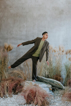 Young businessman balancing on rock in garden