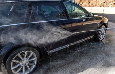 Car washing under the open sky. High-pressure washing car outdoors.