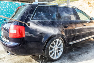 Car washing under the open sky. High-pressure washing car outdoors.