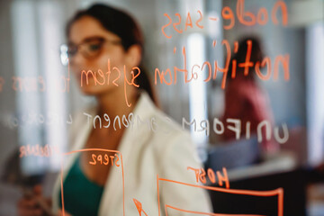 Woman working and writing on the glass board in office. Business, technology, research concept
