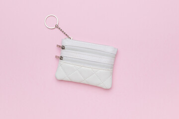 A small women's white purse on a pink background.