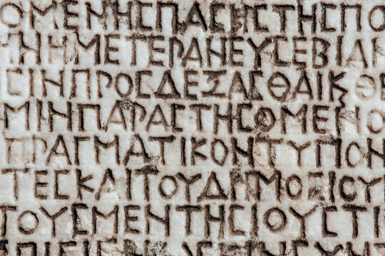 Retro text background. Fragment of ancient inscription (imperial law in ancient Greek language), carved on marble block. Monochrome. Ancient Miletus, Turkey (Turkiye). Ancient art and history concept