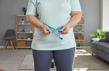 Close up cropped photo of a fat overweight woman wearing sportswear measure the waist with...